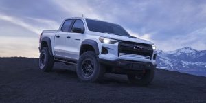 White Chevrolet Colorado pickup truck on a mountain landscape. 